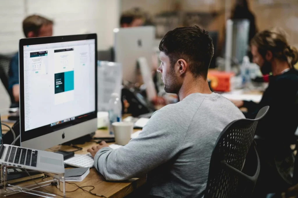Employee using a large monitor for web development at a desk.