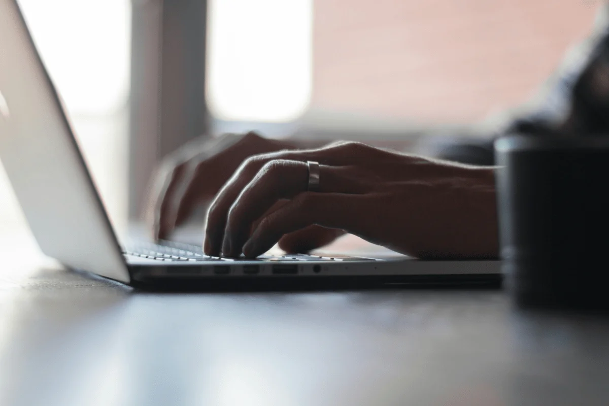 Close-up of hands typing on a laptop with a blurred background.