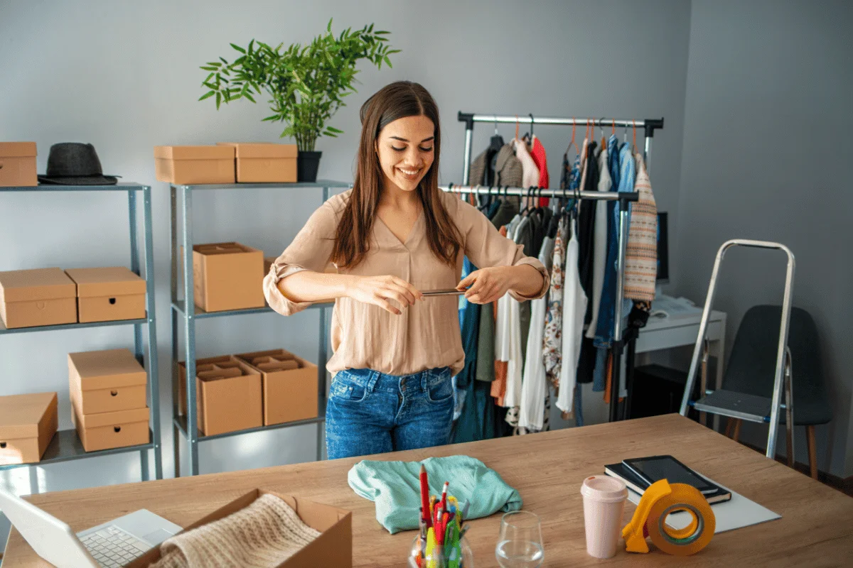 Person packing items in a small business office with boxes and clothes.