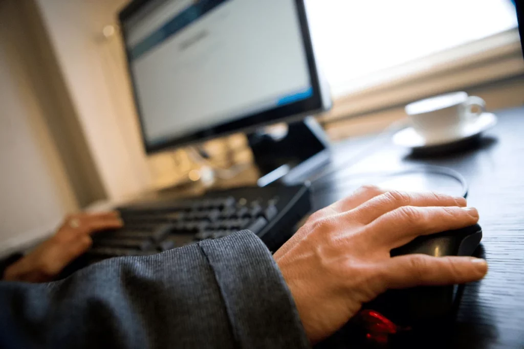 Person working on a computer with a coffee cup in the background.