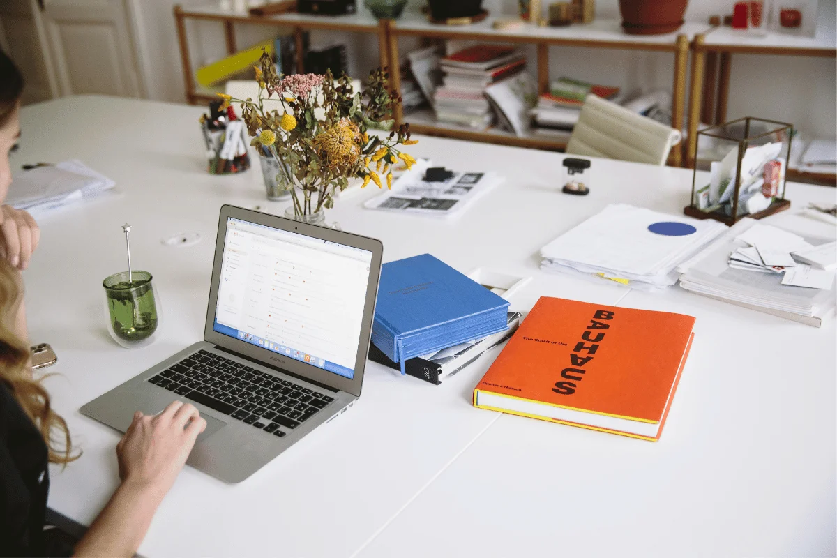 Person using a laptop at a cluttered desk in a home office.