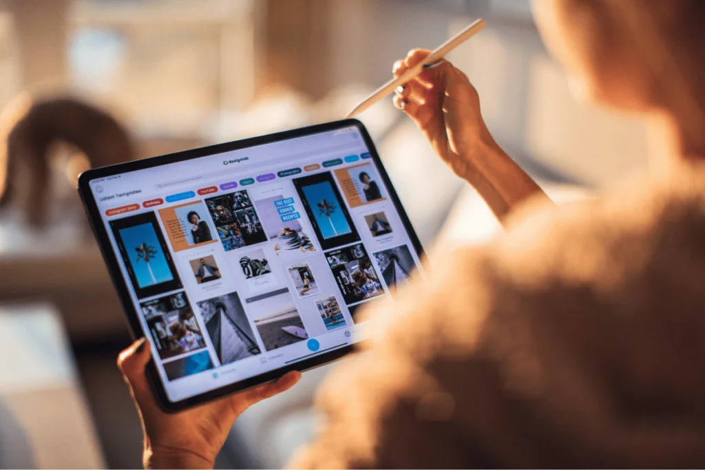 Person using a stylus to browse design templates on a tablet, with a bright, cozy home interior in the background.