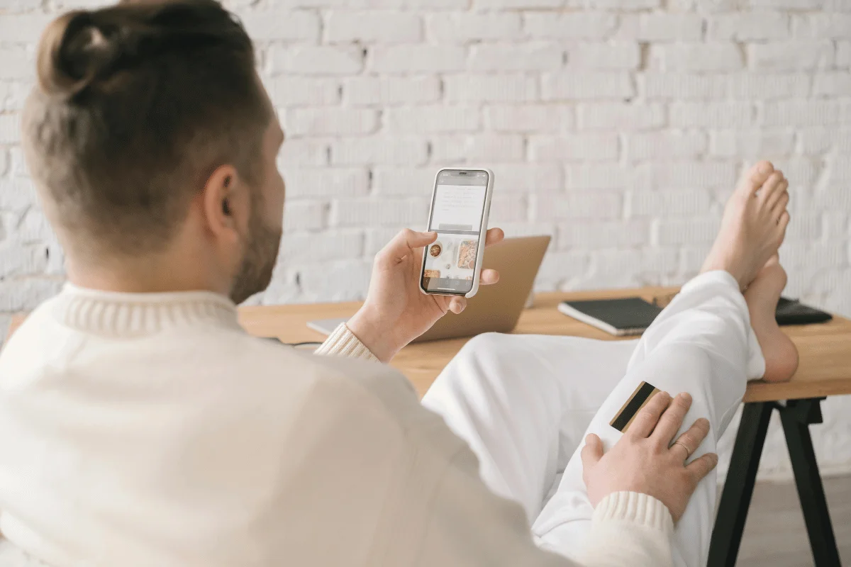 Man shopping online with a smartphone and holding a credit card.