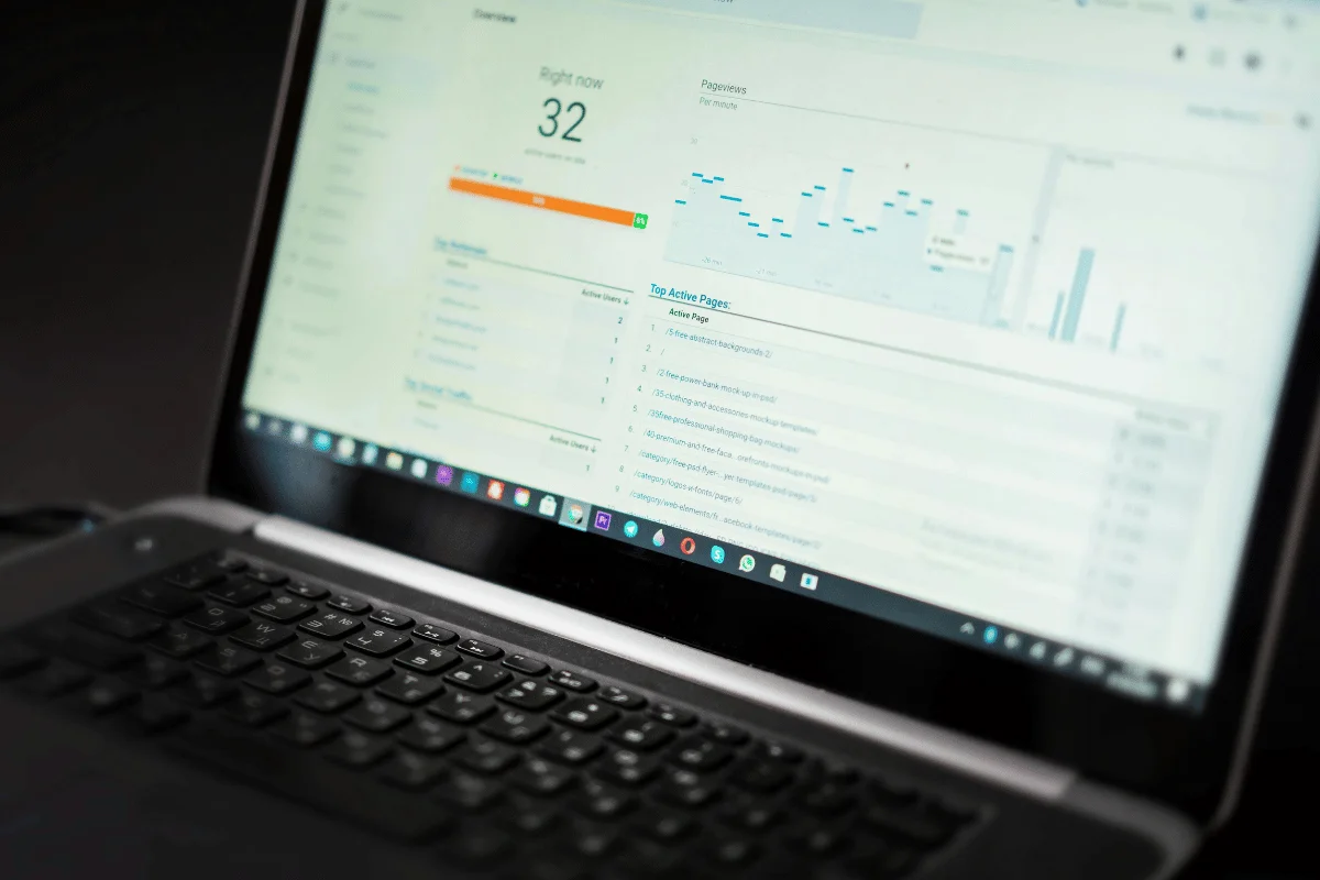 A laptop displays analytics data, with charts, numbers, and lists on the screen. The tone is analytical and focused, suggesting data analysis in progress.