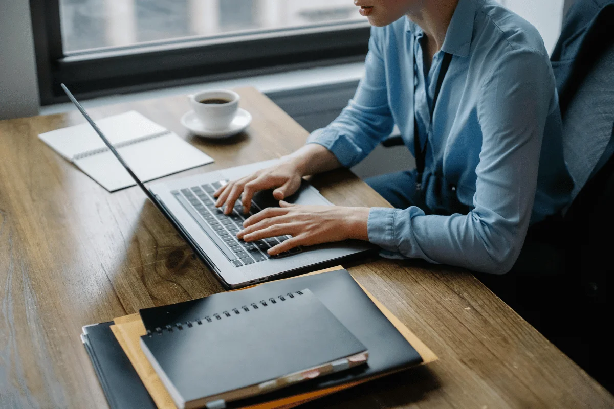 Person working on a laptop in a modern office space with a coffee cup.