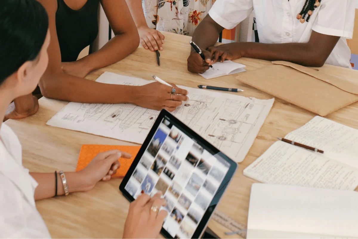 Team collaborating on sketches and ideas at a wooden table.