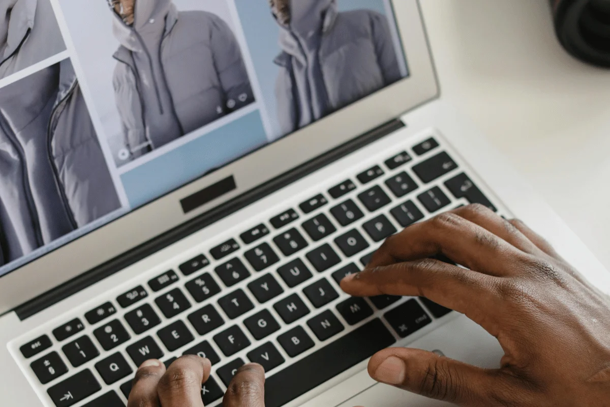 Professional woman in a beige blazer standing by a window, holding a laptop close to her chest.