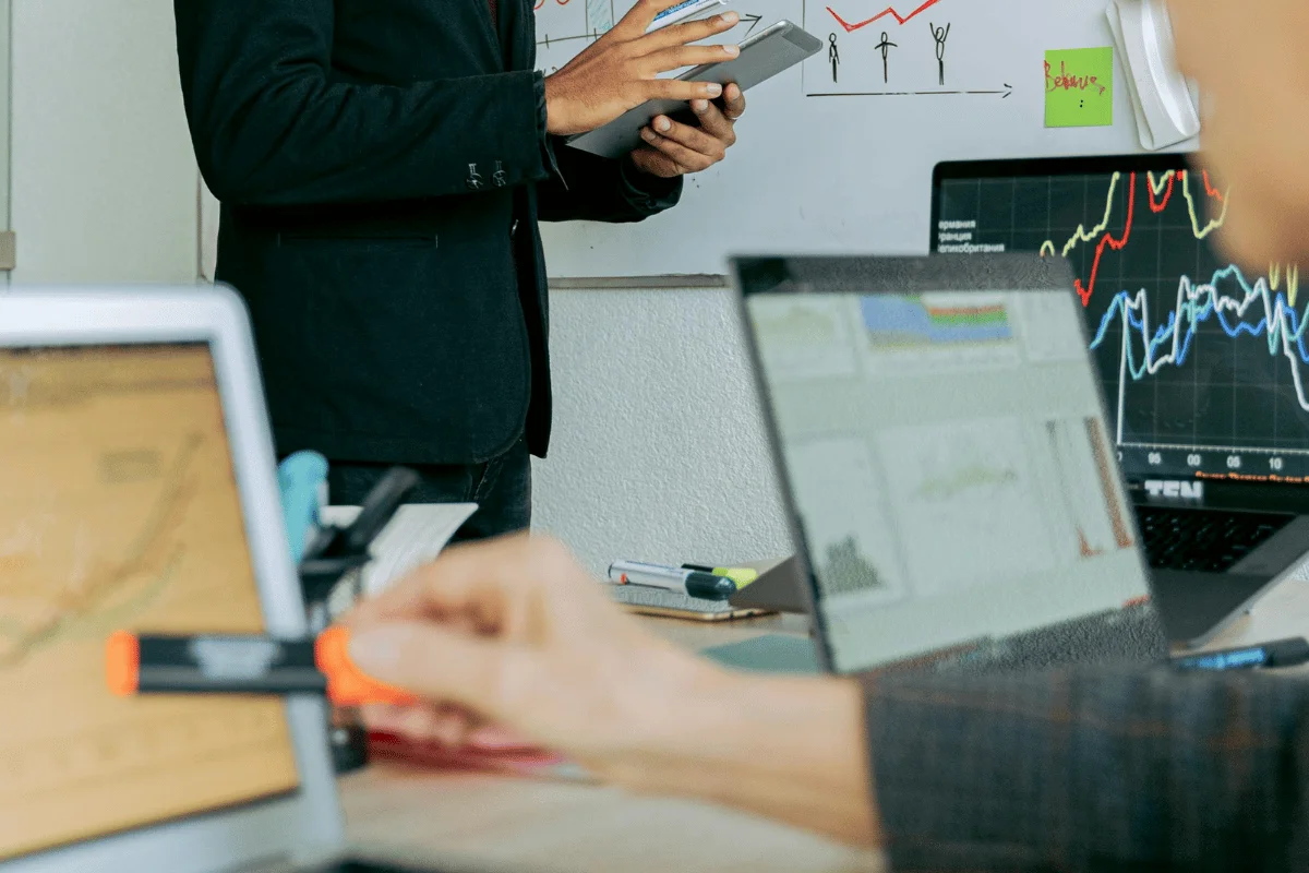 Business team analyzing stock charts on laptops in a meeting.