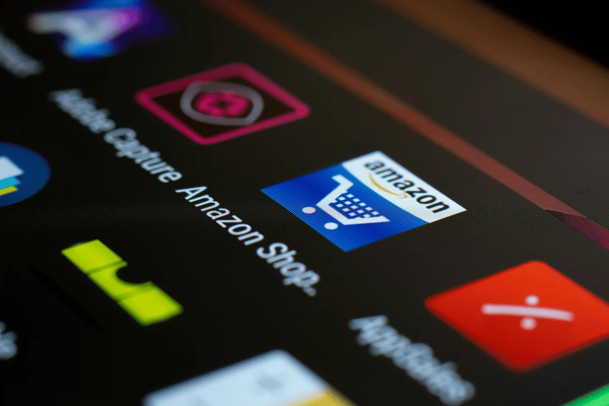 Close-up of a smartphone screen displaying the Amazon shopping app icon, featuring a shopping cart and the Amazon logo.