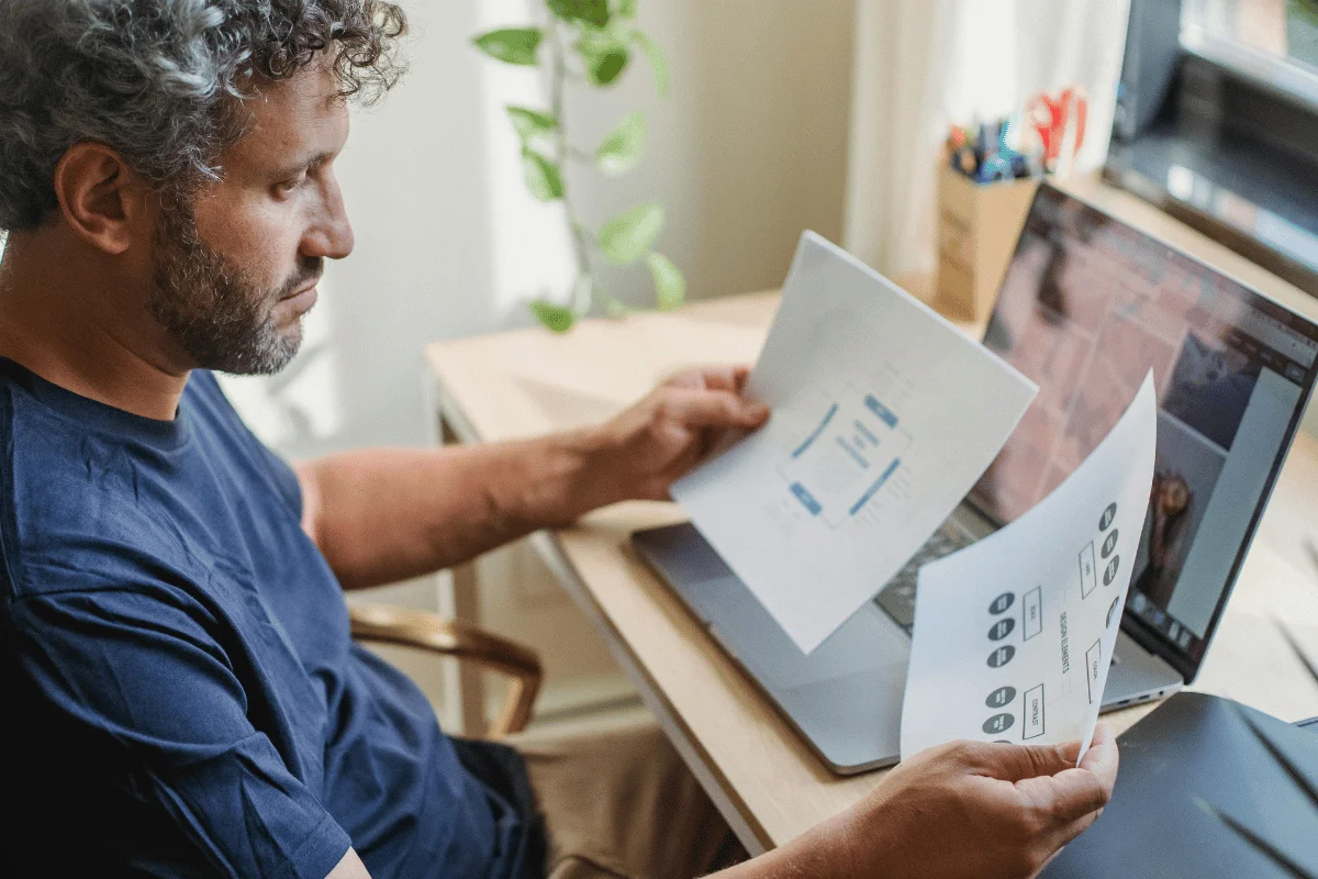 Person analyzing workflow diagrams in front of a laptop.
